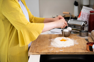 小麦粉の上に卵を落とす、パスタを作っている手元
