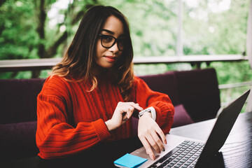 Pensive businesswoman making settings on smartwatch checking notification of organizer application...