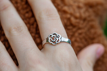 Female hand wearing silver metal ring in the shape of om