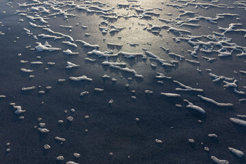 sea foam on sandy beach during sunrise golden hour, texture, background.