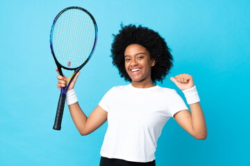 Young African American woman isolated on blue background playing tennis and proud of himself