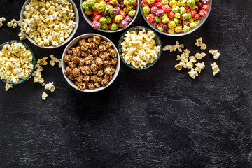 Set of flavored popcorn and soda on black desk top-down space for text