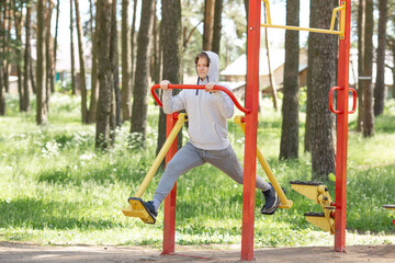 Single young man doing exercises on the sports ground in the park, street workout. Fitness outside. Exercising alone for Covid-19 revention