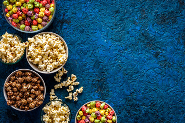 Colorful popcorn in paper box on blue background top view space for text
