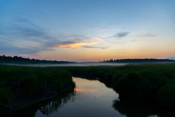 Fototapeta na wymiar Nature at sunset. River and fog in the meadows. Forest on the horizon