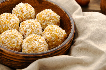 Raw vegan healthy sweets, energy balls with dried fruits and coconut. Brown plate with a napkin. Top view