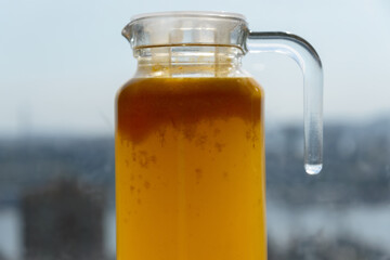 Glass carafe with compote from sea-buckthorn in the kitchen. Home made. Shallow depth of field.