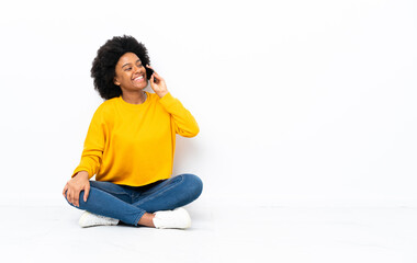 Young African American woman sitting on the floor keeping a conversation with the mobile phone