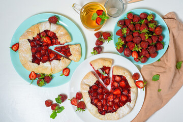 homemade strawberry Biscuit with fresh ripe strawberries on blue and white plates with tea on a light background, top view