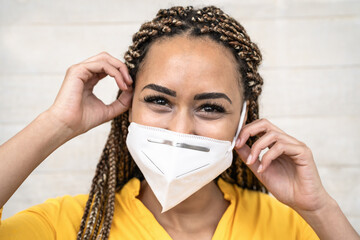Young Afro woman with braids wearing face medical mask portrait - African girl using facemask for...