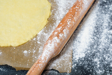 rolling pin for dough with flour scattered on a dark background. top view, close-up, space for text . preparation for making dough at home