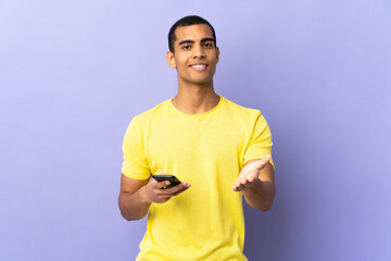 African American man over isolated purple background using mobile phone handshaking after good deal