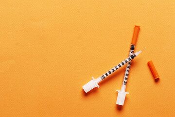 Two insulin syringes on a colored background with place for text.
