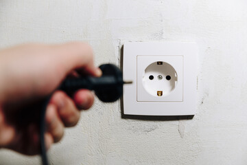 The man's hand inserts the plug from the socket