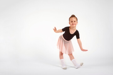 Little girl dressed in dance uniform is dancing over a white background in the studio.
