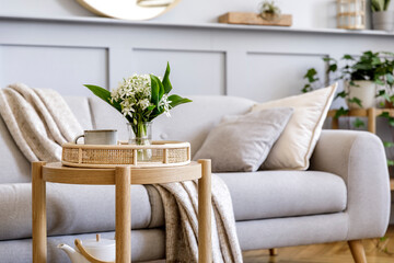  Interior design of scandinavian living room with stylish grey sofa, coffee table, spring flowers, decoration, pillows, plaid, tray and elegant personal accessories in modern home decor. - obrazy, fototapety, plakaty