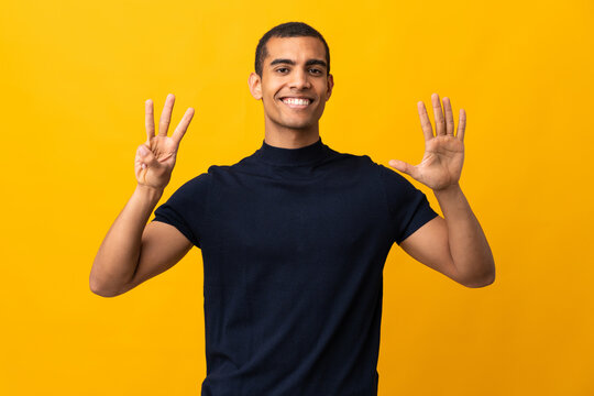 African American man counting numbres over isolated yellow background