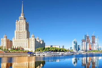  picturesque moscow city skyline landmark against blue sky background. Cityscape of russian capital. Old and new skyscrapers reflection on water of moscow river. Pleasure boats moored to embankment © vaalaa