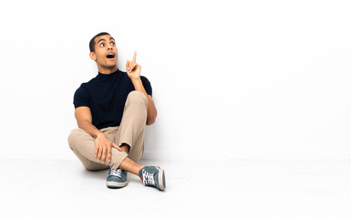 African American man sitting on the floor thinking an idea pointing the finger up