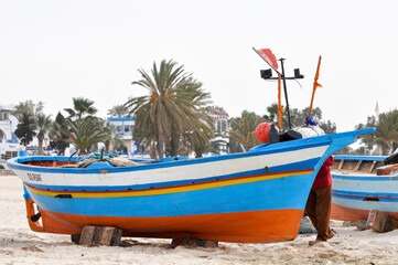 Fototapeta na wymiar Hammamet, Tunisia- February 07, 2009: Tunisian Fishing boats on the beach with traditional colors.