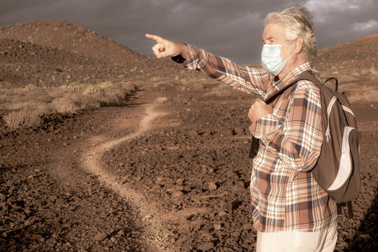 Senior man wearing face mask enjoys nature outdoors in the mountains - active retired lifestyle. Partial conquest of freedom after coronavirus lockdown