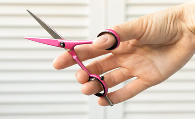 Close-Up Of Hand Holding Scissors Against White Background