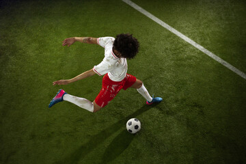 Top view of caucasian football or soccer player on green background of grass. Young male sportive...