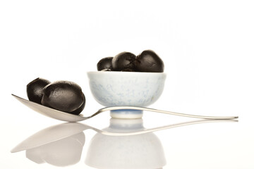 Pickled spicy black olives, close-up, on a white background.