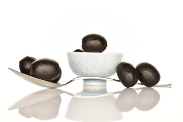 Pickled spicy black olives, close-up, on a white background.