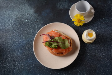 Breakfast with sandwich with cereals bread and salmon, soft cheese and poached eggs 