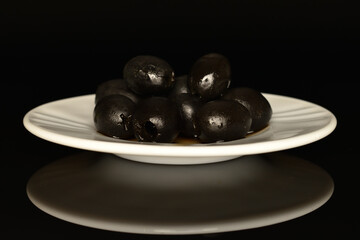 Pickled spicy black olives, close-up, on a black background.