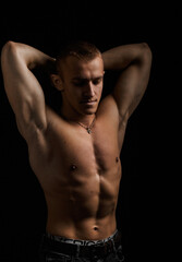 Fototapeta na wymiar Young muscular bodybuilder posing over black background.