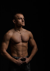 Fototapeta na wymiar Strong sports man - fitness model showing his perfect body isolated on black background with copyspace