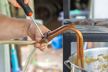 Close-up of young man hands holding a screwdriver to tighten the rubber strap to let the craft beer...