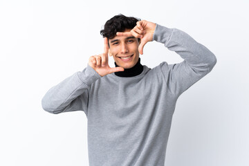 Young Argentinian man over isolated white background focusing face. Framing symbol