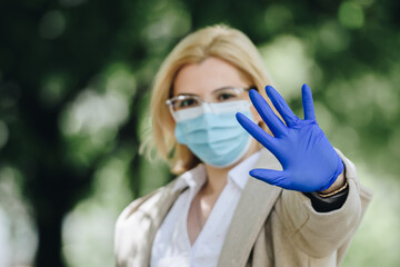 woman wearing medical mask and gloves with hand in front of her face