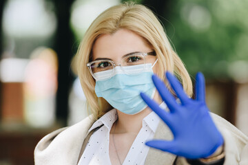 woman wearing medical mask and gloves with hand in front of her face