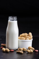 Fresh peanut milk in bottle with peanut on dark stone table . Healthy vegan eating