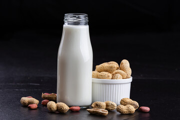 Fresh peanut milk in bottle with peanut on dark stone table . Healthy vegan eating