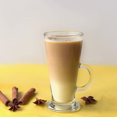 Glass of layered latte coffee on a yellow surface with cinnamon sticks and anise stars