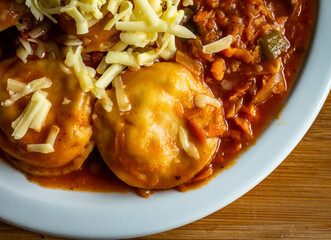 Homemade pasta called sorrentinos. Flour dough filled with grated cheese covered sauce. Homemade food.