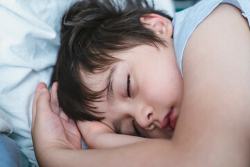 Fototapeta na wymiar Adorable kid deep sleep in bed in the morning, Child sleeping on bed. Little boy taking a peaceful nap, Children health care concep