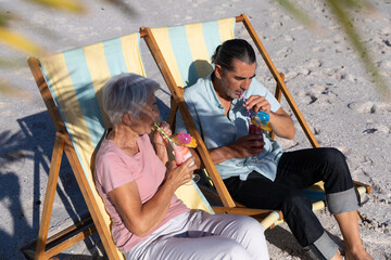 Senior Caucasian couple sitting on deck chairs at the beach.