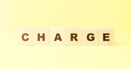 word charge made with wooden blocks on yellow background