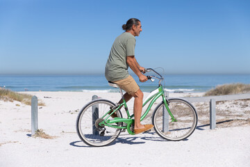 Naklejka premium Senior Caucasian man riding a bike at the beach