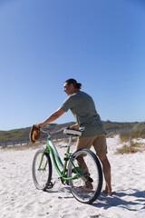 Fototapeta premium Senior Caucasian man carrying a bike at the beach 