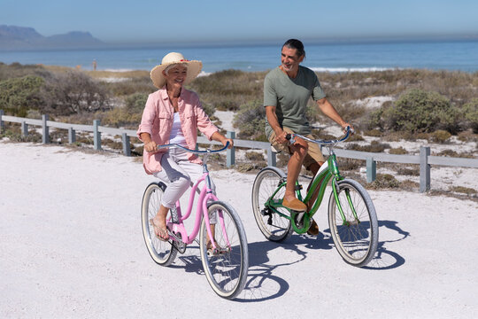 Senior Caucasian couple riding a bike at the beach