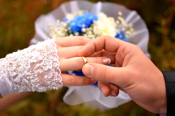 The groom's hand puts the ring on the bride's finger close-up