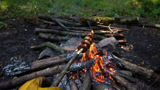 Cooking banger (sujuk) on campfire in forest, Camping in nature