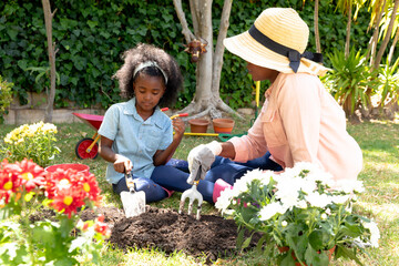 African American girl and her grandmother planting flowers at their garden